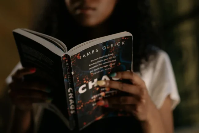 A woman reading a book with the title "Chaos"